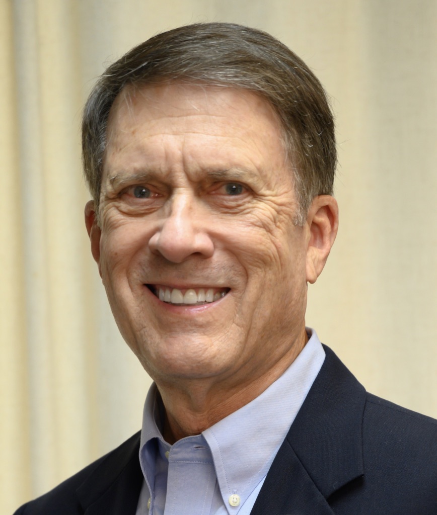 A person wearing a suit and tie smiling at the camera

Description automatically generated