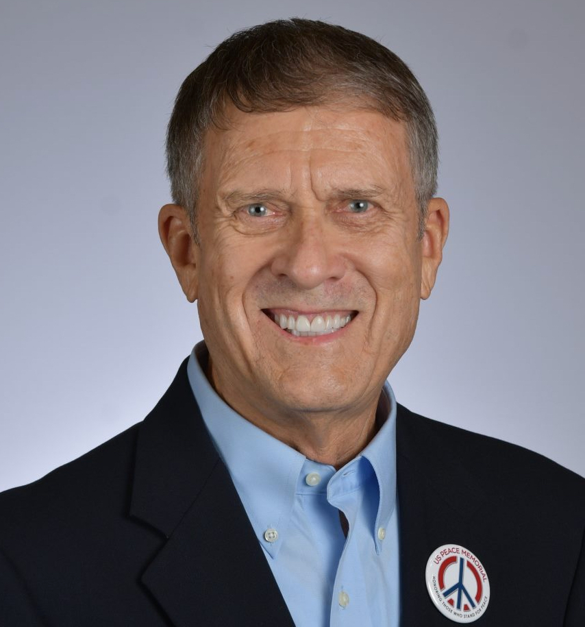 A person in a suit smiling

Description automatically generated